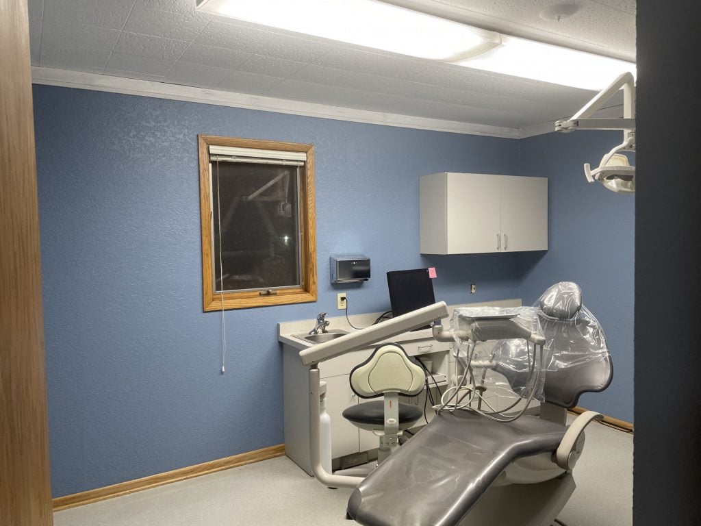 Dental chair in front of cabinets and sink