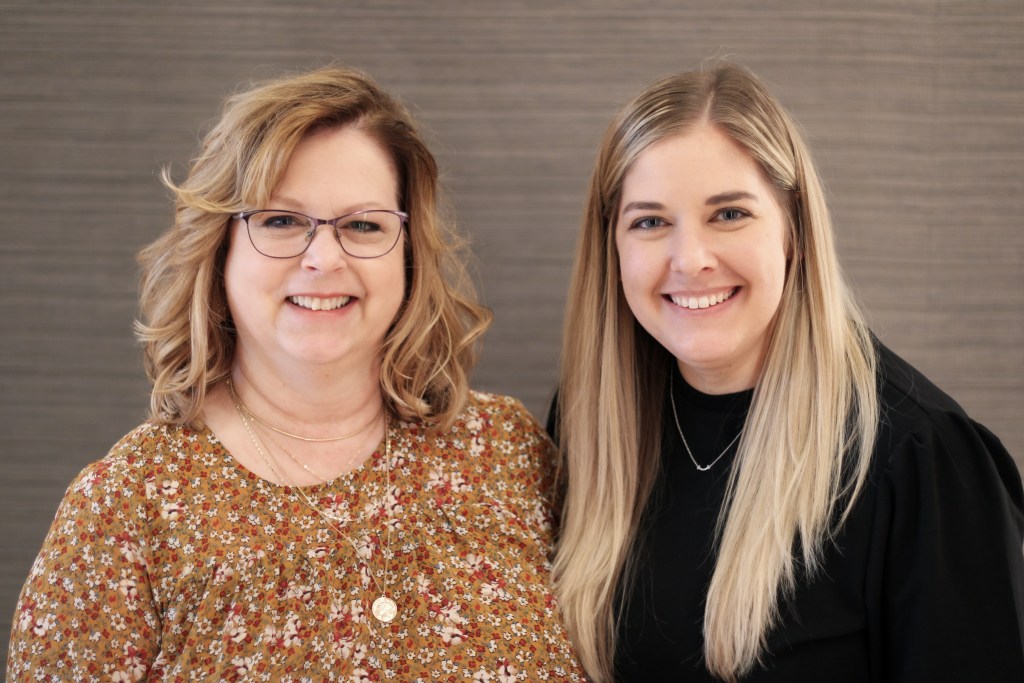 Two staff members smiling at {PRACTICE_NAME}
