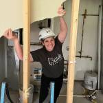 Smiling woman standing between wall studs during construction