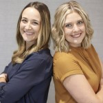 2 smiling female staff posing back to back