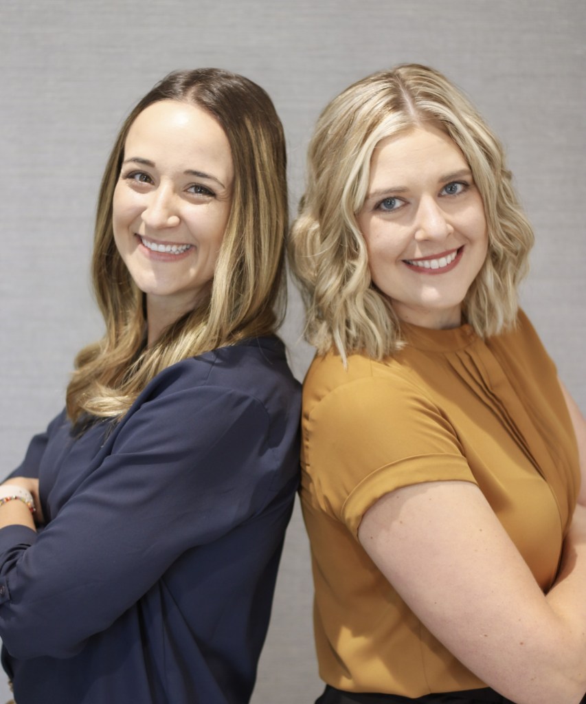 2 smiling female staff posing back to back